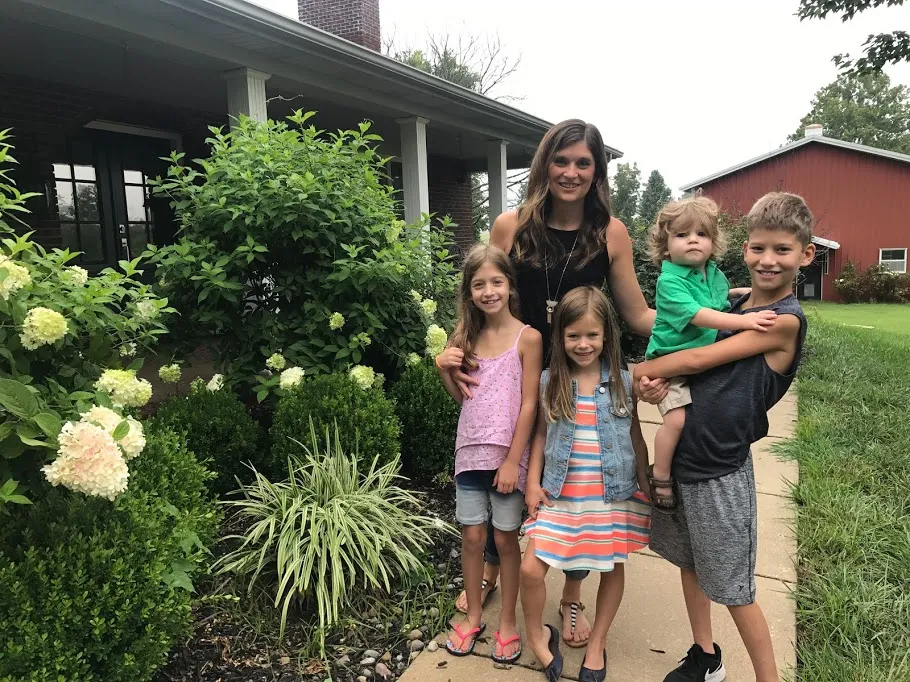 Emily and the four children on the front path, hydrangeas beside them and the red barn behind