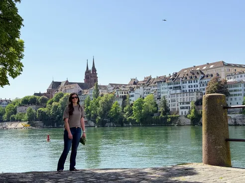 Emily on the Rhine embankment, the old town and the Minster's twin spires rising across the green water