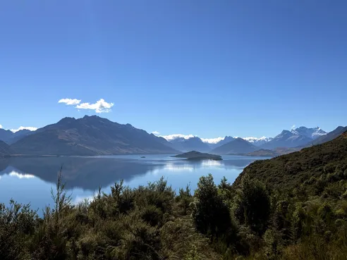 The view from Bennetts Bluff over the lake, a wooded island in the middle and snow-capped peaks along the far end