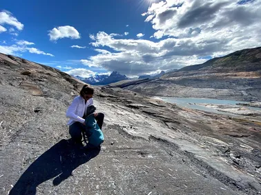 Emily crouched on a great sloping slab of glacier-scoured rock, the glacier and meltwater lake below
