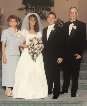 Christy on her wedding day between her parents and her new husband, all four on the church steps