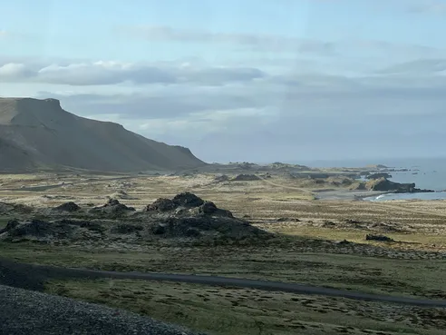 The east coast seen from the car, a flat-topped mountain above a plain of lava mounds running down to the sea