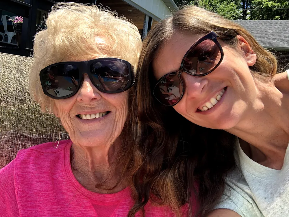 Emily and her Mamaw cheek to cheek in the sun, both in sunglasses and both laughing