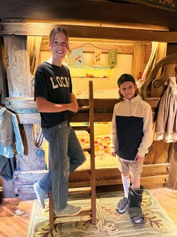 Mia on the ladder and Case beside her in front of the hobbit bunk beds with their patchwork quilts
