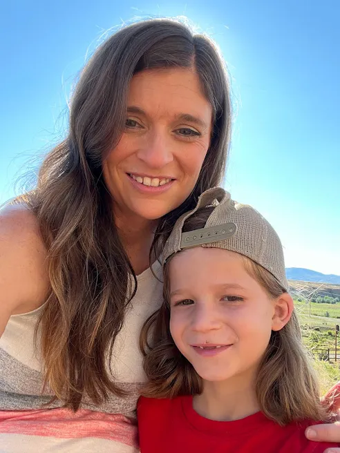 Emily and Case close together in the sun, Case in a backwards cap, open country behind them