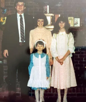 An Easter portrait by the brick fireplace, the parents behind and the two girls in pale dresses in front