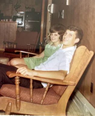 Emily's parents as teenagers squeezed into one wooden rocking chair, both laughing at the camera