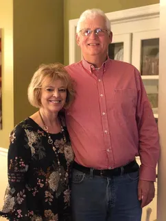 Emily's parents standing together in the kitchen doorway, his arm round her shoulder