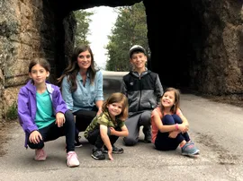 Emily and the four children crouched together in the mouth of a rough-cut rock tunnel on the Needles Highway