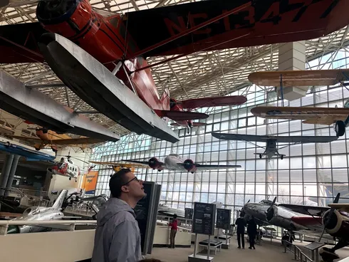 Josh looking up at vintage aeroplanes hung from the glass roof of the Museum of Flight