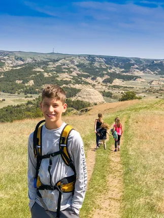 Preston with a backpack on a badlands trail, his three siblings walking on ahead of him