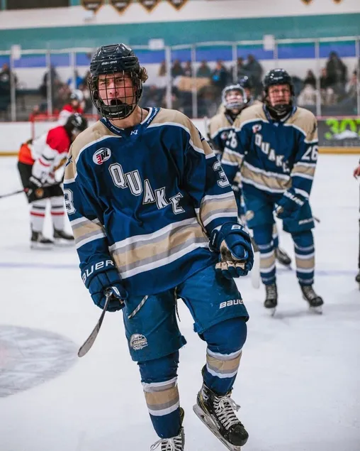 Preston skating up the ice in a blue and gold Quake jersey, team mates behind him