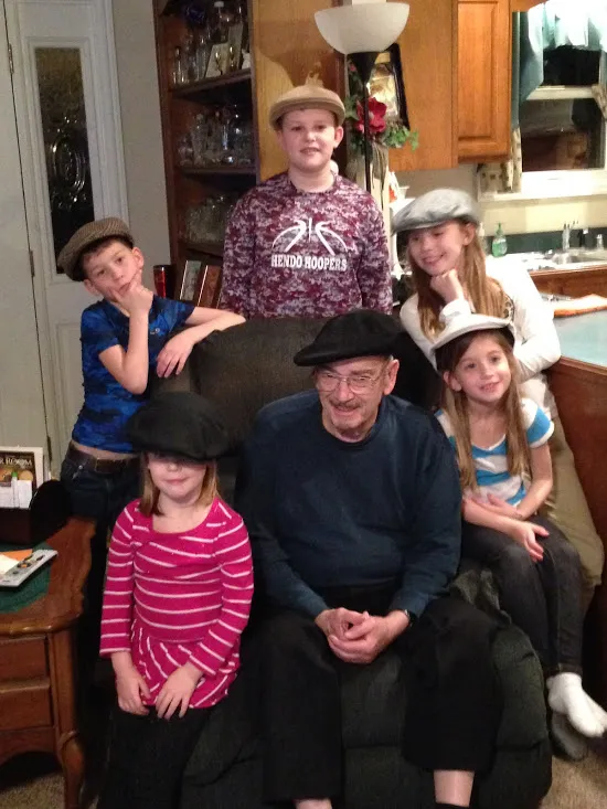 Papaw in his armchair with five grandchildren gathered round him, every one of them wearing a flat cap