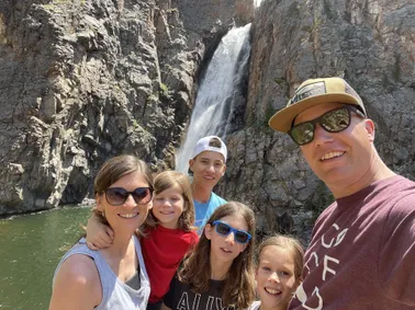 All six of them close to the camera in front of Porcupine Falls, the water dropping down the rock face behind them