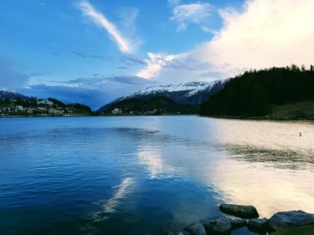The lake at St Moritz at dusk, the town on the left shore and snow-topped peaks catching the last light