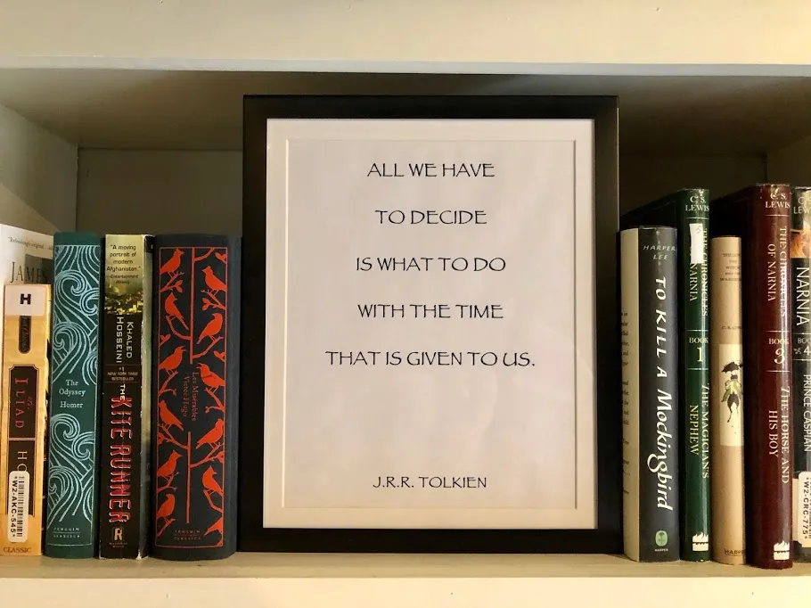 A framed Tolkien quote on a bookshelf, all we have to decide is what to do with the time that is given to us, flanked by Narnia and To Kill a Mockingbird