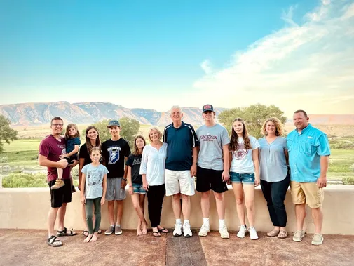 The whole extended family lined up along the patio wall at the ranch, the Big Horn escarpment and open country behind them