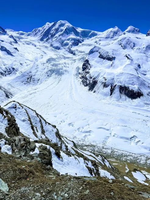 The Gorner glacier curving down between snow-covered peaks under a deep blue sky