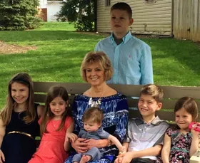 Emily's mother on a garden bench surrounded by six grandchildren, the baby on her lap