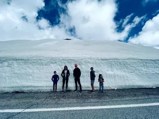 Emily and four of the children standing along a cut snow bank taller than all of them, at the roadside